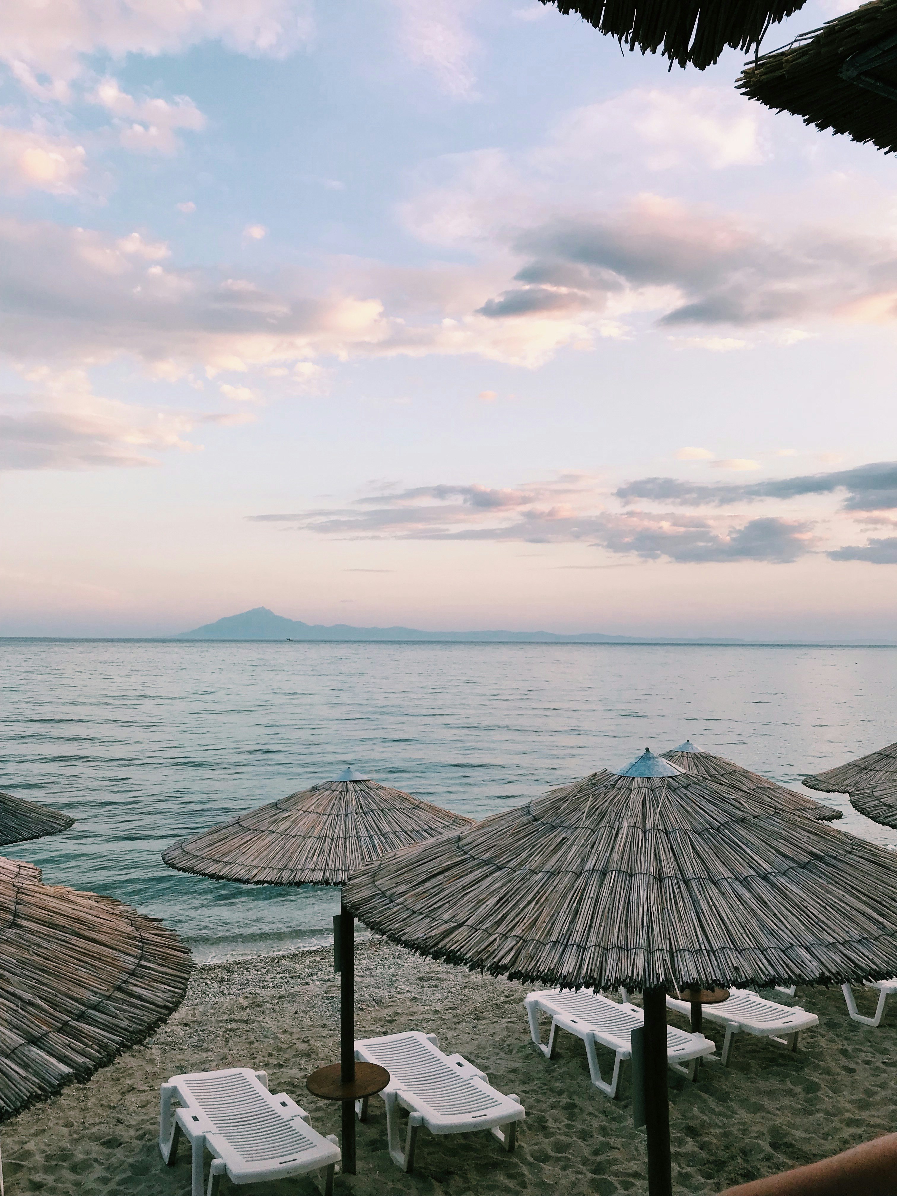 white loungers and brown straw parasols in beach